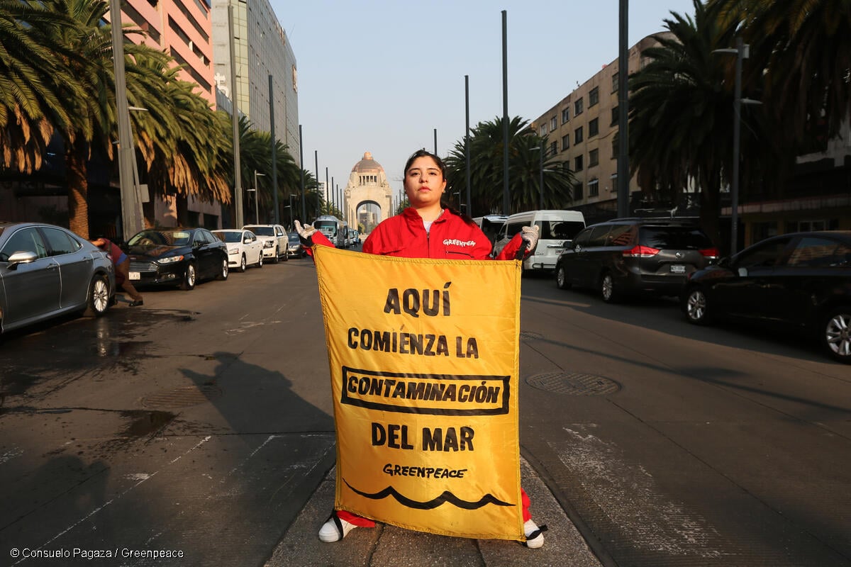 Activista de Greenpeace México sostiene una manta con el mensaje "Aquí comienza la contaminación del mar" para crear conciencia sobre la contaminación por plásticos.