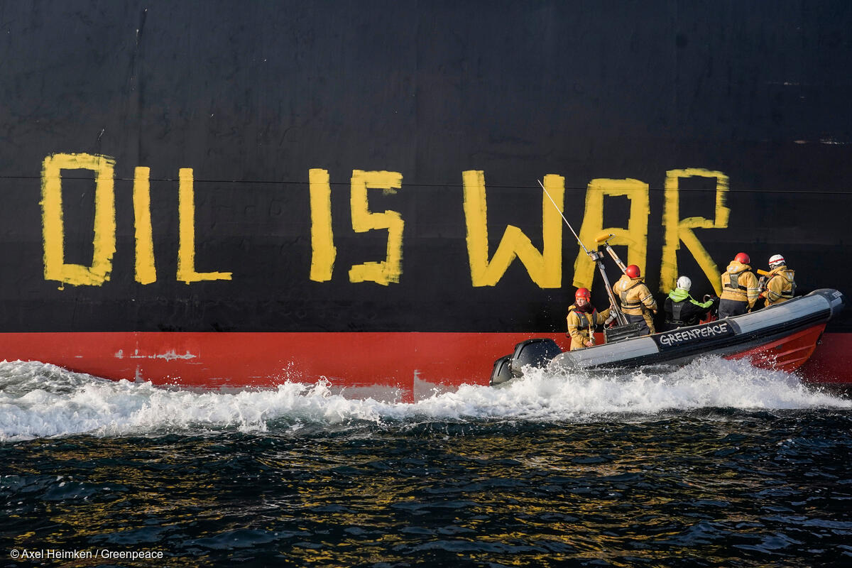 Activistas de Greenpeace en el mar pintando "EL PETRÓLEO ES LA GUERRA" en el costado de un petrolero ruso, en protesta contra las importaciones que financian la guerra en Ucrania.
