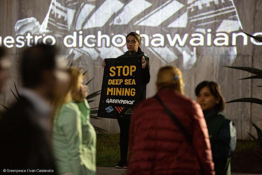 Activista de Greenpeace México sosteniendo una manta con el mensaje "STOP DEEP SEA MINING" (ALTO A LA MINERÍA SUBMARINA).