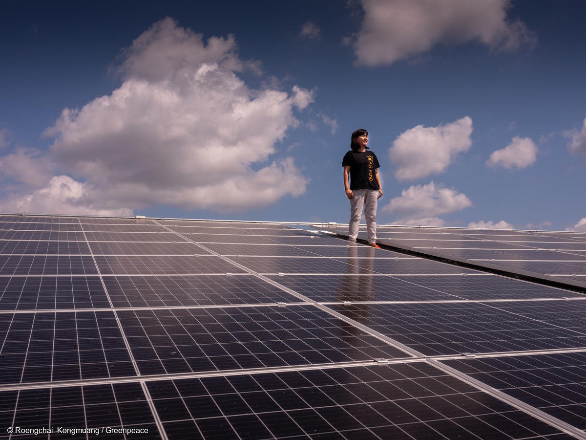 Mujer parada viendo al horizonte sobre paneles solares.
