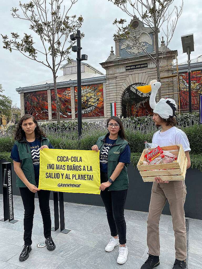 Retrato de tres activistas de Greenpeace México en Toluca sosteniendo una manta en la se lee "Coca-Cola, ¡No más daños a la salud y al planeta".