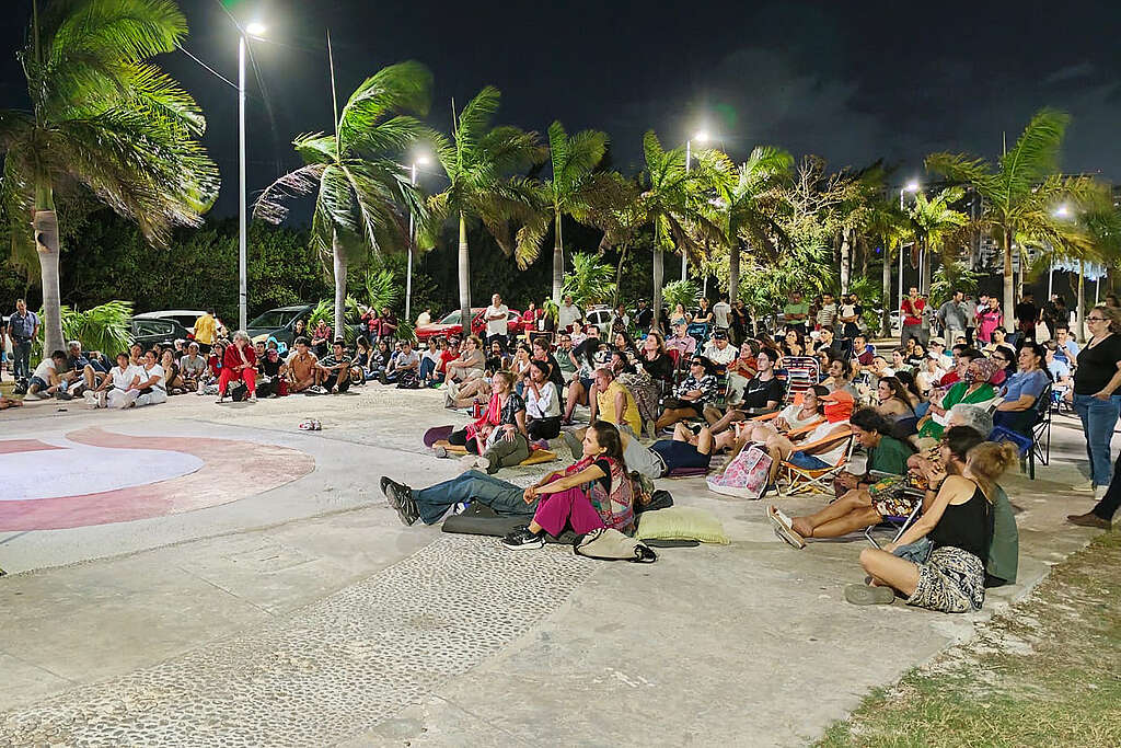 Un grupo de personas sentadas en una explanada en Tajamar mientras ven el documental "Voces de la Selva Maya" de Greenpeace México.