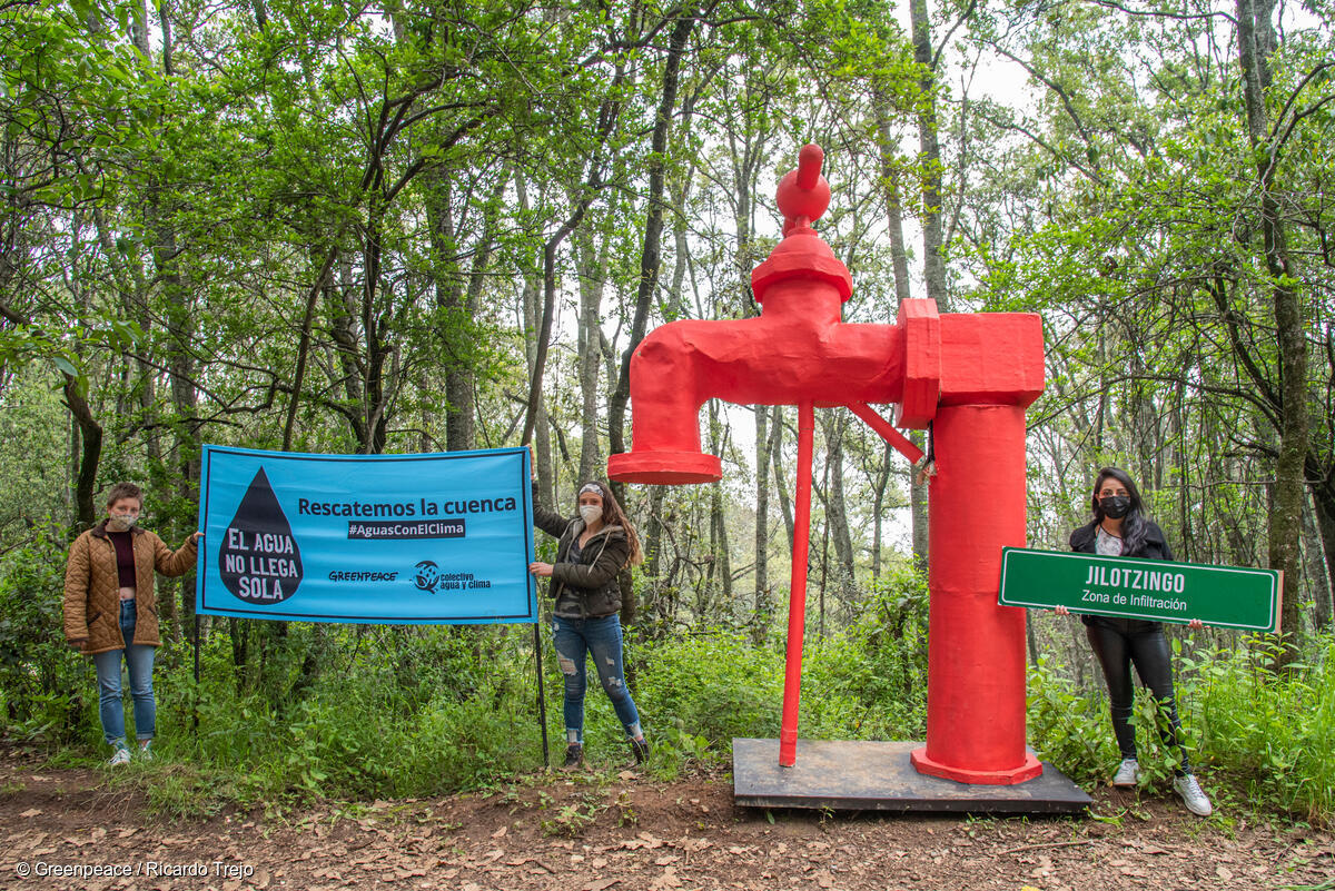 3 activistas entre árboles sostienen un grifo gigante y la leyenda "Rescatemos la cuenca. #AguasConElClima".