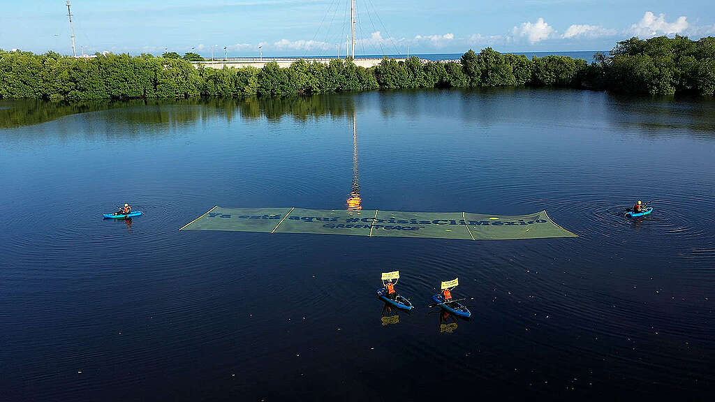 Activistas de Greenpeace México en lanchas sobre lago en Tabasco preparando una manta para acción contra la crisis climática. Activistas de Greenpeace México en lanchas sobre lago en Tabasco preparando una manta para acción contra la crisis climática.