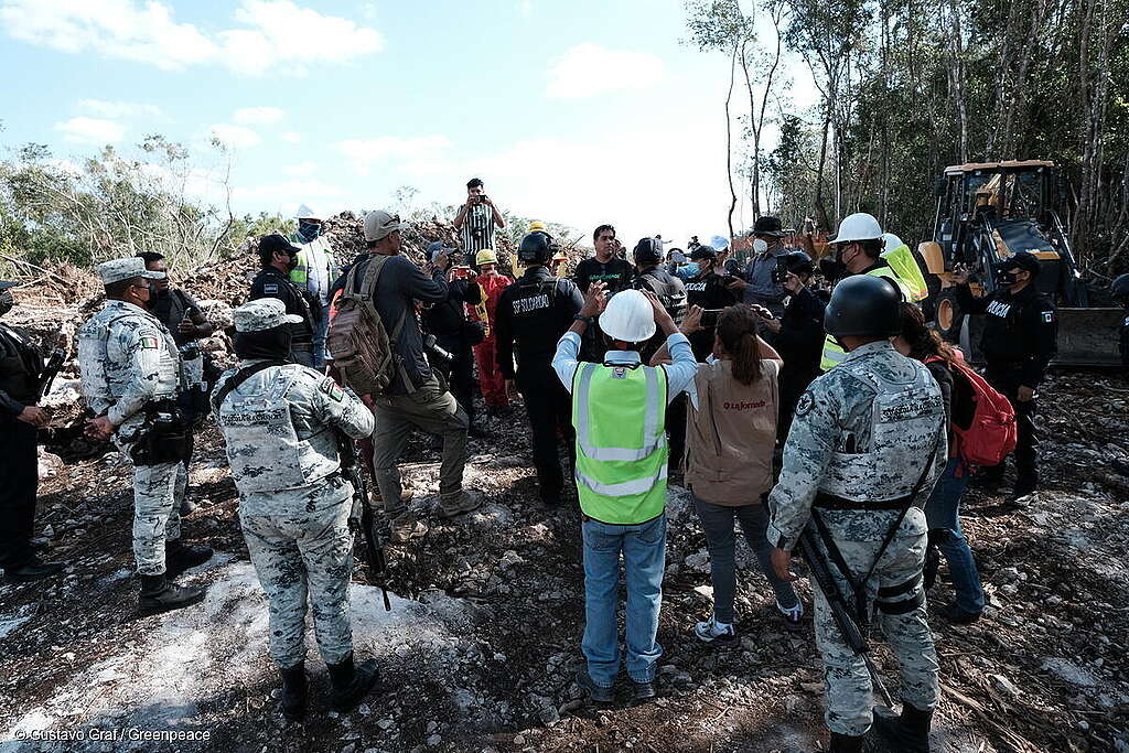 Fotografía de un grupo de activistas, representantes de otros grupos, trabajadores de la obra, prensa y Guarda Nacional en medio de acción simbólica donde activistas detienen simbólicamente las obras de construcción del tramo 5 del Tren Maya,