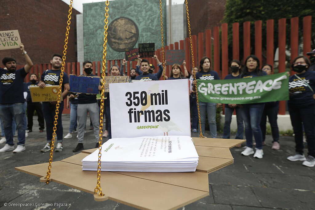 Activista de Greenpeace México protestando con pancartas detrás de una representación simbólica de las 350 mil firmas recabadas para exigir que no haya retrocesos en las reformas a la Ley de Residuos y la Ley de Economía Circular.