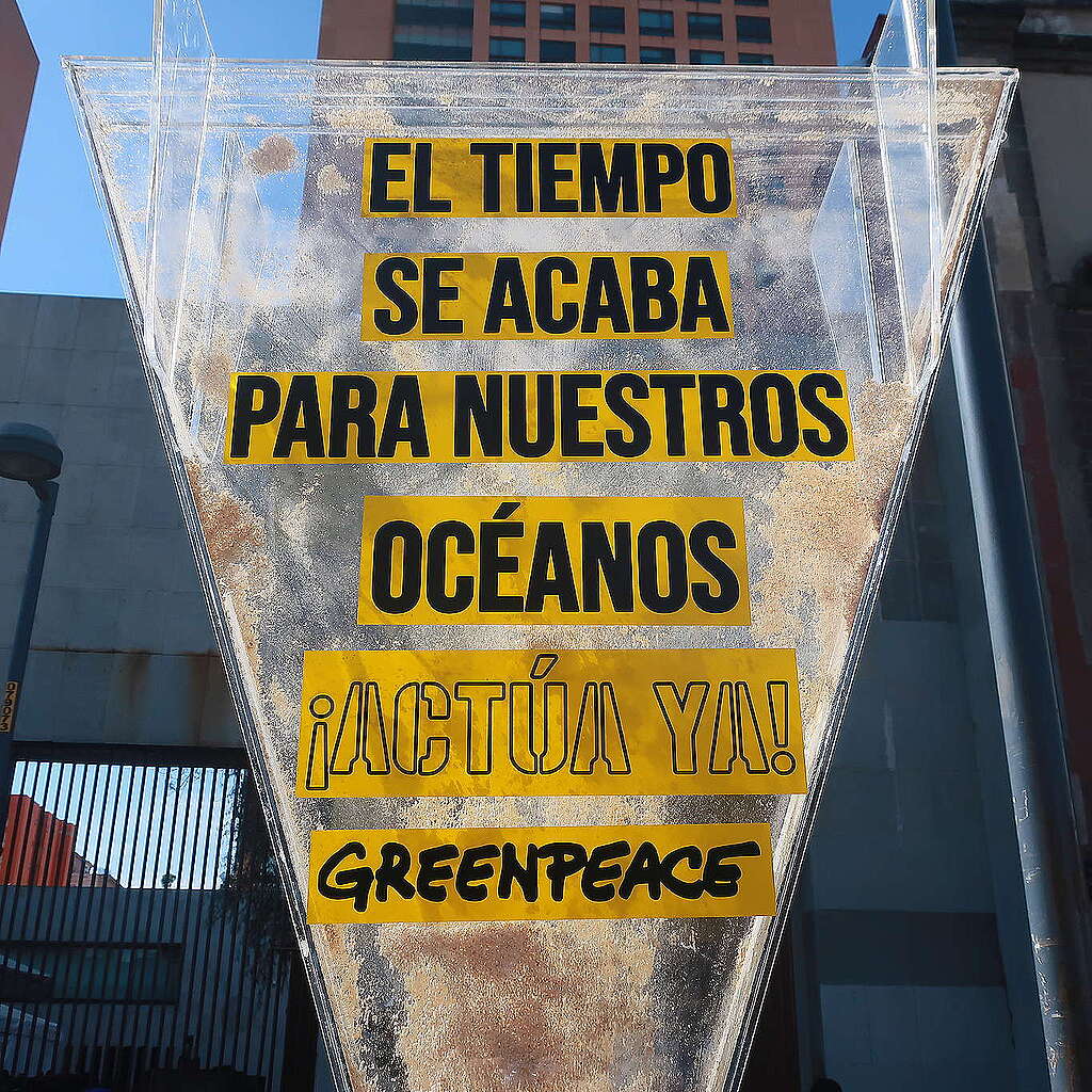 Fotografía de un reloj de arena gigante en el que se lee "El tiempo se acaba para nuestros océanos, actúa ya".