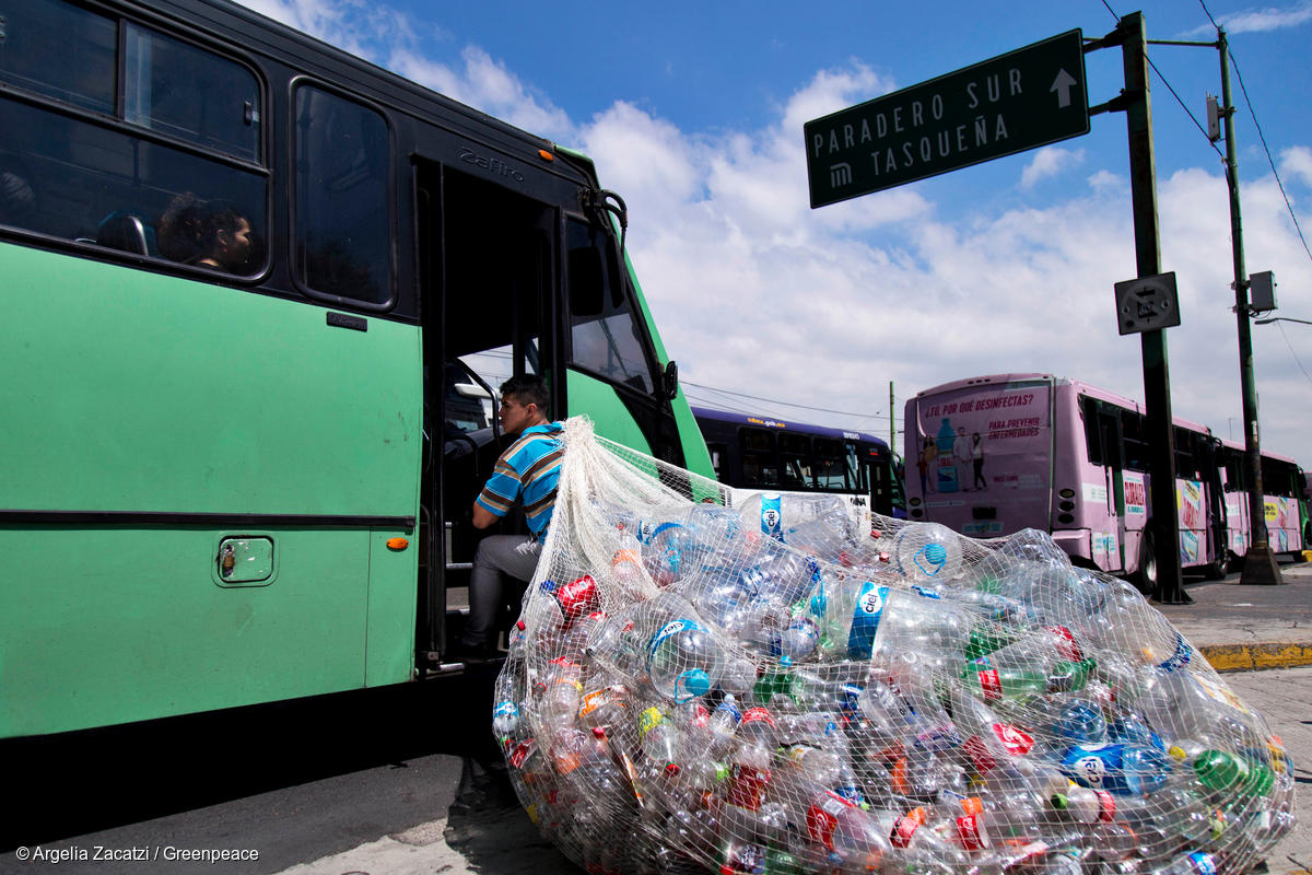 En la imagen, una persona carga una enorme bolsa con botellas de plástico mientras sube al transporte público para ilustrar el problema del consumo de plástico.