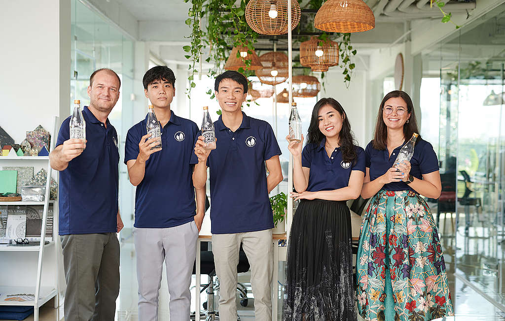 Fotografía de cinco personas del equipo de trabajo de Glassia sosteniendo una botella de vidrio.