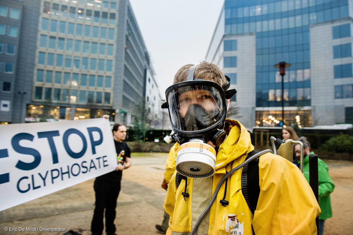 Activistas de Greenpeace, con ropa protectora y mascarillas, exhiben una pancarta frente a la Comisión Europea con el lema "Stop Glifosato".