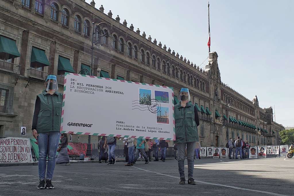 Dos personas del staff de Greenpeace México frente al Palacio Nacional sostienen una carta gigante a manera de una petición simbólica.