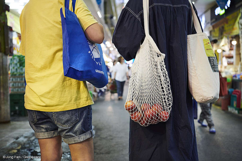 Fotografía de dos personas cargando bolsas reutilizables durante sus compras en el mercado.