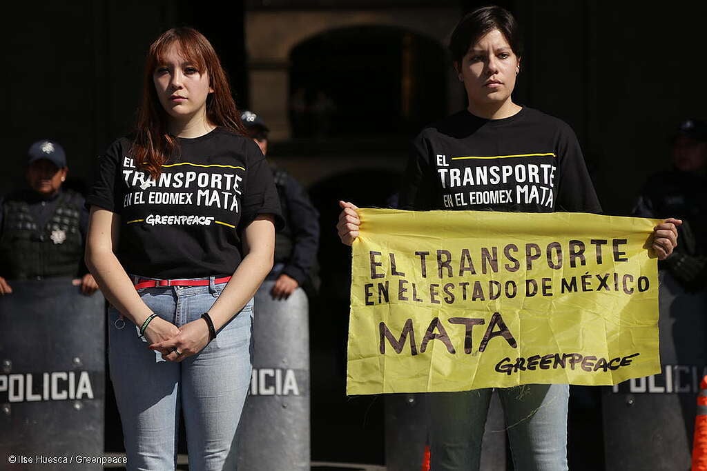 Fotografía de 2 activistas de Greenpeace México, una de ellas sotiene una pancarta que dice "El transporte en el Estado de México mata".