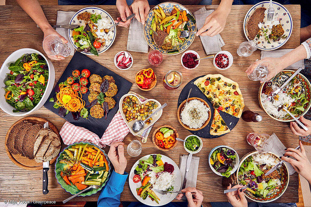 Una familia comiendo una variedad de alimentos de origen vegetal en casa.