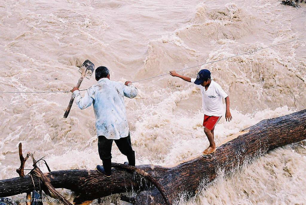 Fotografía que muestra las consecuencias del huracán Stan en México durante 2005, se muestra un adulto y un niño tratando de caminar entre inundaciones.