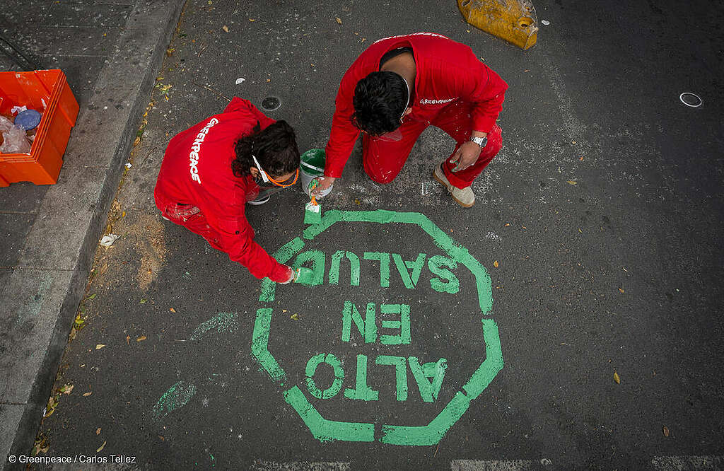 Dos activistas de Greenpeace "etiquetan" Av. Insurgentes con el sello "Alto en Salud" para pedir ciclovías permanentes.