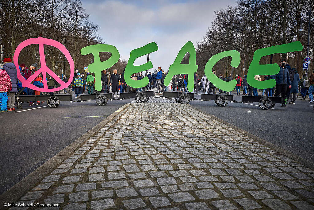 Símbolo de paz y la palabra "peace" del logo de Greenpeace en una manifestación.