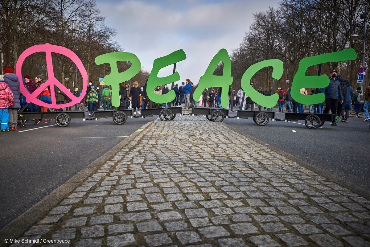 Símbolo de paz y la palabra "peace" del logo de Greenpeace en una manifestación.