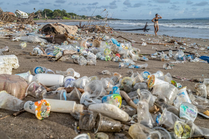 Een toerist loopt over een strand tussen de plastic vervuiling op Bali.