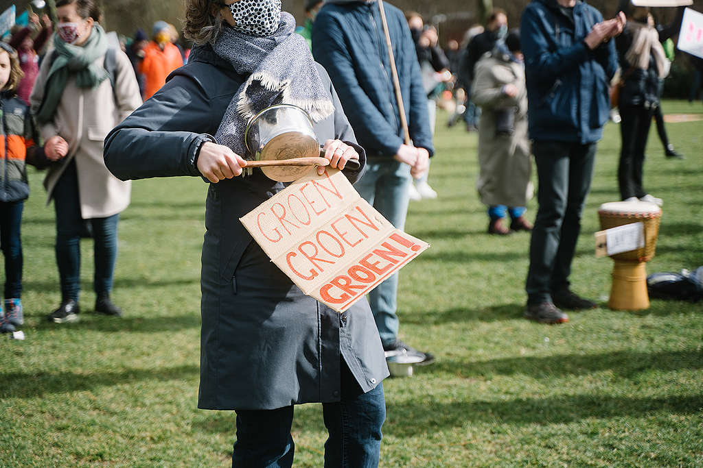 Een vrouw houdt tijdens een klimaatdemonstratie een protestbord omhoog waarop staat: groen, groen, groen. 