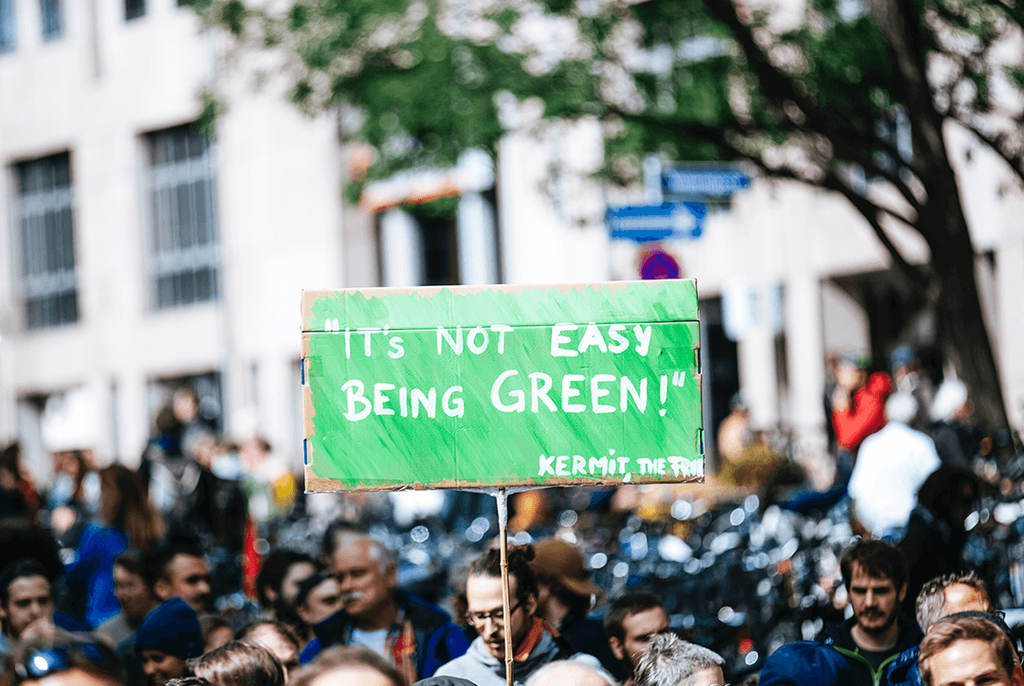 Een protestbord omhoog met de tekst: It's not easy being green'.