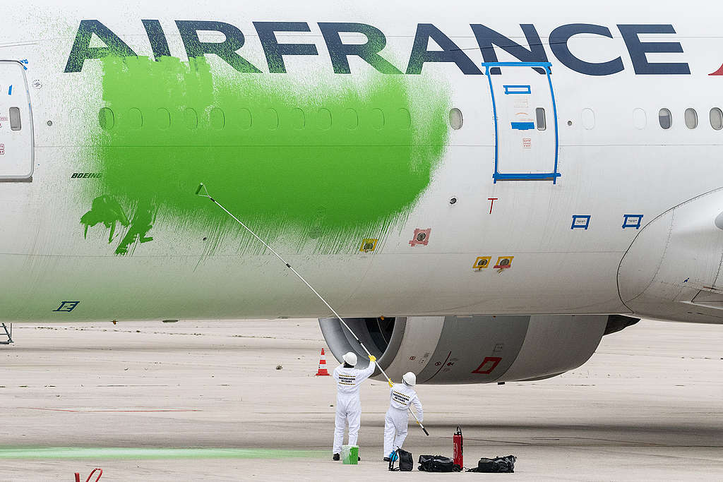 Greenpeace actievoerders protesteren tegen greenwashing in de luchtvaart door een vliegtuig groen te schilderen.