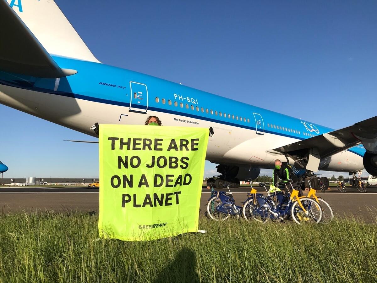 Activists Demand Climate Conditions Bailout at Schiphol, Amsterdam Activist is holding a banner saying " There are no jobs on a dead planet" in front of a parked KLM aircraft at Schiphol Airport.
Activists from Greenpeace Netherlands cycled onto the runway at Schiphol Airport demanding the Dutch government regulates the billions that are being spent to support big polluting industries during the pandemic.
Joris Thijssen, director of Greenpeace Netherlands, said:
"KLM gets a bailout for billions of euros even though the company has no climate plan and pays almost no taxes. Efforts to help the industry get through this crisis shouldn't plunge us even deeper into the climate crisis. Blank check bailouts for big polluters are unacceptable. The government must impose climate-based conditions on these bailout billions.”