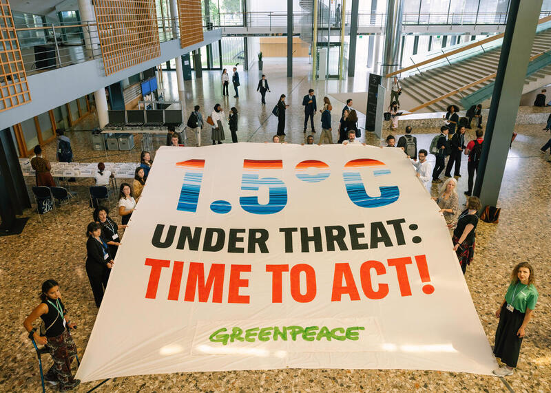 Greenpeace onthult spandoek binnen VN-locatie Klimaatconferentie Bonn en roept op tot krachtigere actie voor grens van 1,5 graden opwarming.