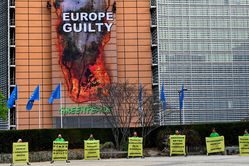 Greenpeace-aksjon ved EU-kommisjonens hovedkvarter i Brussel. Et 30 meter langt banner etterligner et hull som er brent gjennom bygningen, og viser Amazonas i flammer, med meldingen: «Amazonas brenner – Europa skyldig» .