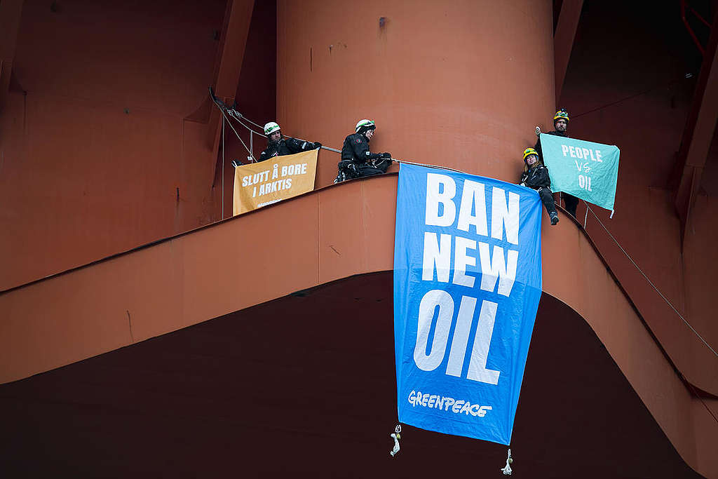 Greenpeace-aktivister på oljerigg med bannere som sier "Slutt å bore i Arktis", "Ban new oil" og "People vs oil".