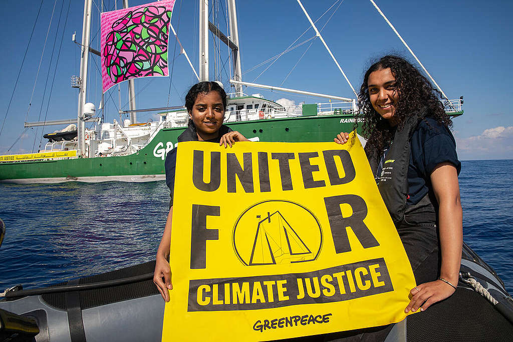 Klimaforkjemperne Watan Mohammed fra Sudan og Alia Hammad from Egypt holder et banner for kampanjen "United for Climate Justice" foran Greenpeace-skipet Rainbow Warrior i Middelhavet, i forkant av klimatoppmøtet i Egypt i 2022. 