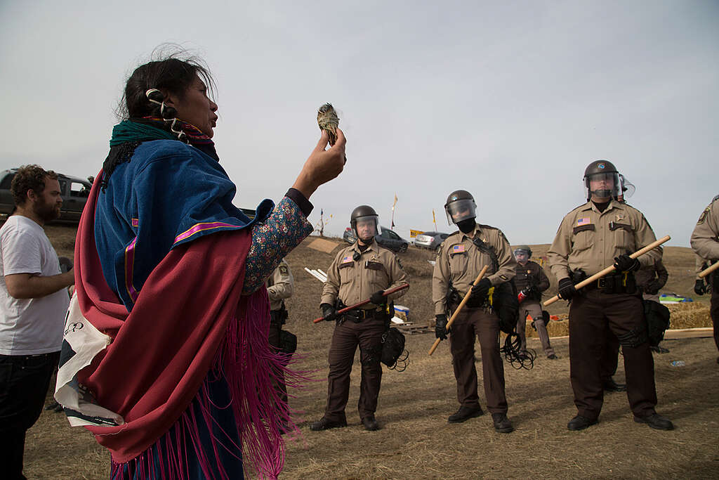 En urfolksaktivist holder opp salvie mens politi og nasjonalgarde konfronterer urfolk og støttespillere som forsøker å blokkere Dakota Access Pipeline. 