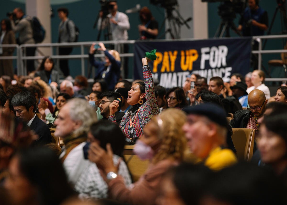 People's Plenary at COP29 in Baku. © Marie Jacquemin / Greenpeace En aktivist løfter armen i solidaritet på et folkemøte under fjorårets klimatoppmøte, COP29 Baku i Aserbajdsjan. © Marie Jacquemin / Greenpeace