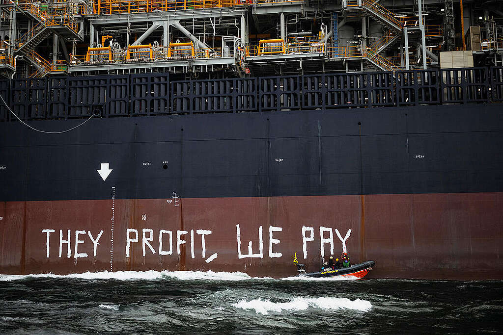 Aktivister fra Greenpeace International maler budskapet "They profit, we pay" på siden av produksjonsskipet som Equinor vil bruke på Rosebank-feltet i Storbritannia.