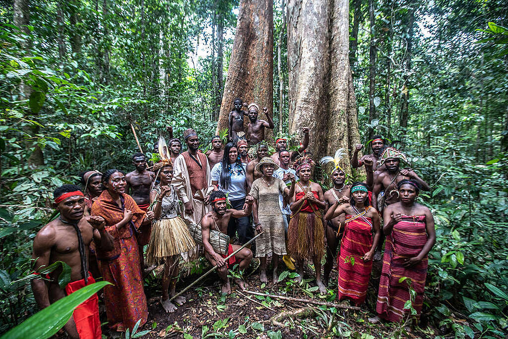 Nathalia Kycendekarun Apurinã, an Amazonian Indigenous youth leader (centre, with blue flowers) along with other international and West Papuan participants gather in front of a Merbau (Intsia bijuga) tree. © Jurnasyanto Sukarno / Greenpeace