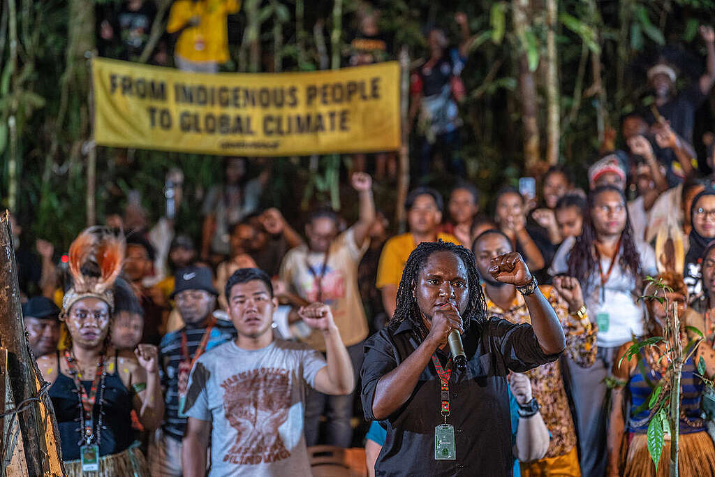 Rossyana Zine Kogoya (with microphone) leads 89 Indigenous participants in reading the Sira Declaration during the Forest Defender Camp on 26 September 2025 in the customary forest of the Tehit-Knasaimos people of West Papua.