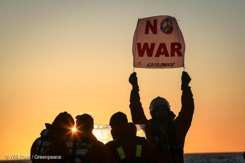 Greenpeace-aktivister håller upp en skylt med texten "No War"