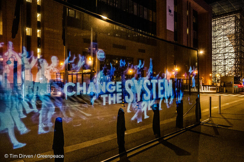 Texten "Change the system" lyser upp en gata i Bryssel genom ett hologram