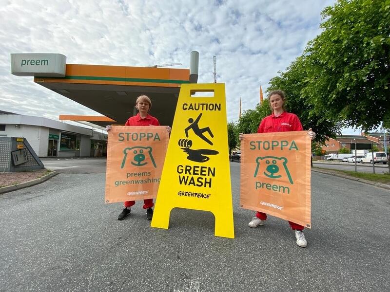 Aktivister utanför Preems bensinstation med skylt som säger caution green wash