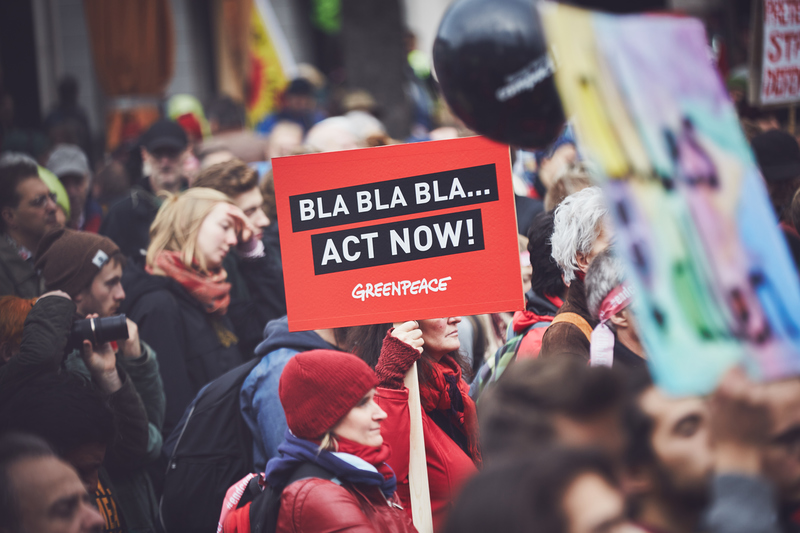 Demonstration under FNs klimatförhandlingar me en skylt som säger Bla, bla, bla. Act Now!