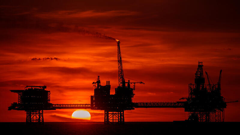 Oljeplattformar i solnedgång till havs