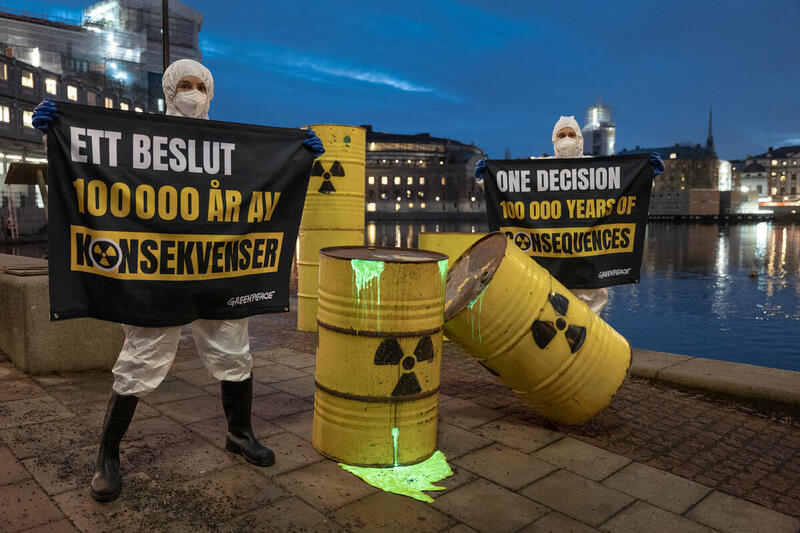 Aktivister utanför Sveriges riksdag med tunnor som ska föreställa kärnavfall och en banner som säger ett beslut 100 000 år av konsekvenser.