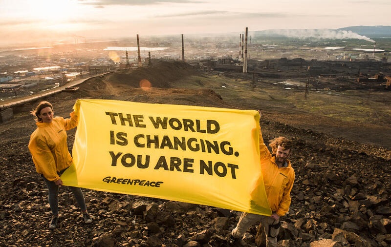 Greenpeace-aktivister lyfter upp en banner med texten "världen förändras, men det gör inte ni" i staden Norilsk i Arktis.