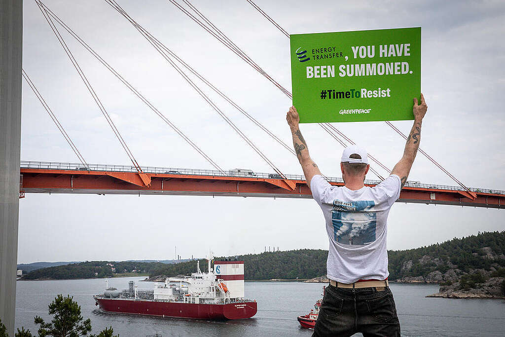 Activists Remind Energy Transfer of Court Date in Sweden. © Will Rose / Greenpeace Aktivist håller upp skylt för att påminna Energy Transfer om en kommande rättegång. © Will Rose / Greenpeace