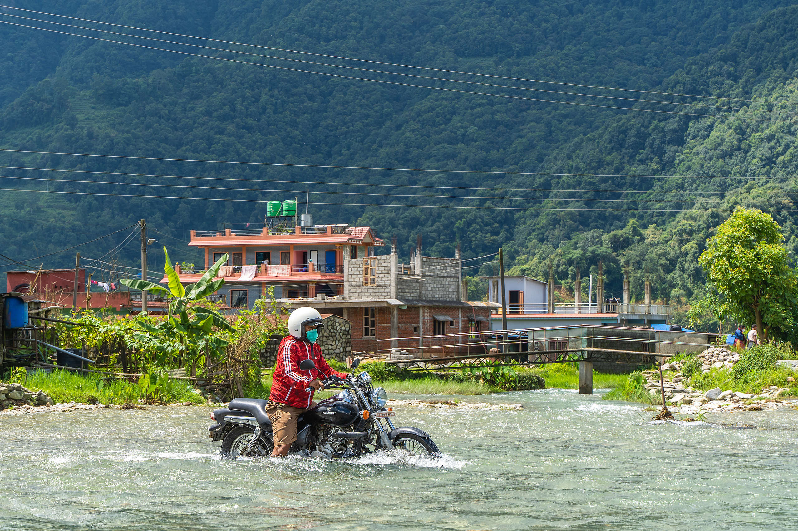 2020年7月，尼泊爾的季風帶來暴雨，使河水暴漲導致淹水，一位Pame村的居民騎著摩托車穿過淹水的道路。