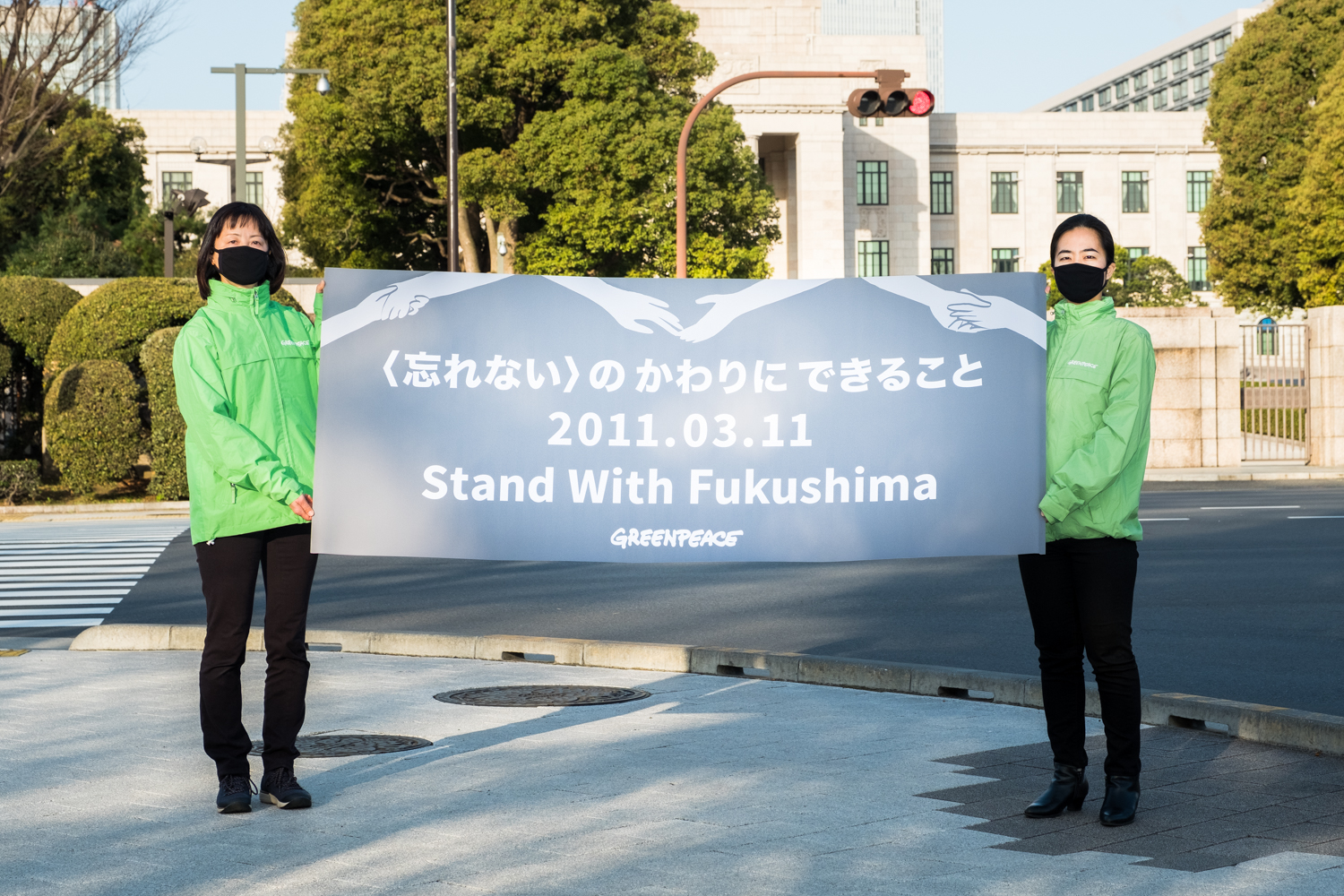 2021年3月11日,綠色和平東京辦公室在國會大廈前,手舉「與福島同行」標語,呼籲日本政府轉向再生能源的未來。