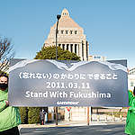2021年3月11日，綠色和平東京辦公室在國會大廈前，手舉標語倡議，呼籲日本政府轉向再生能源的未來。
