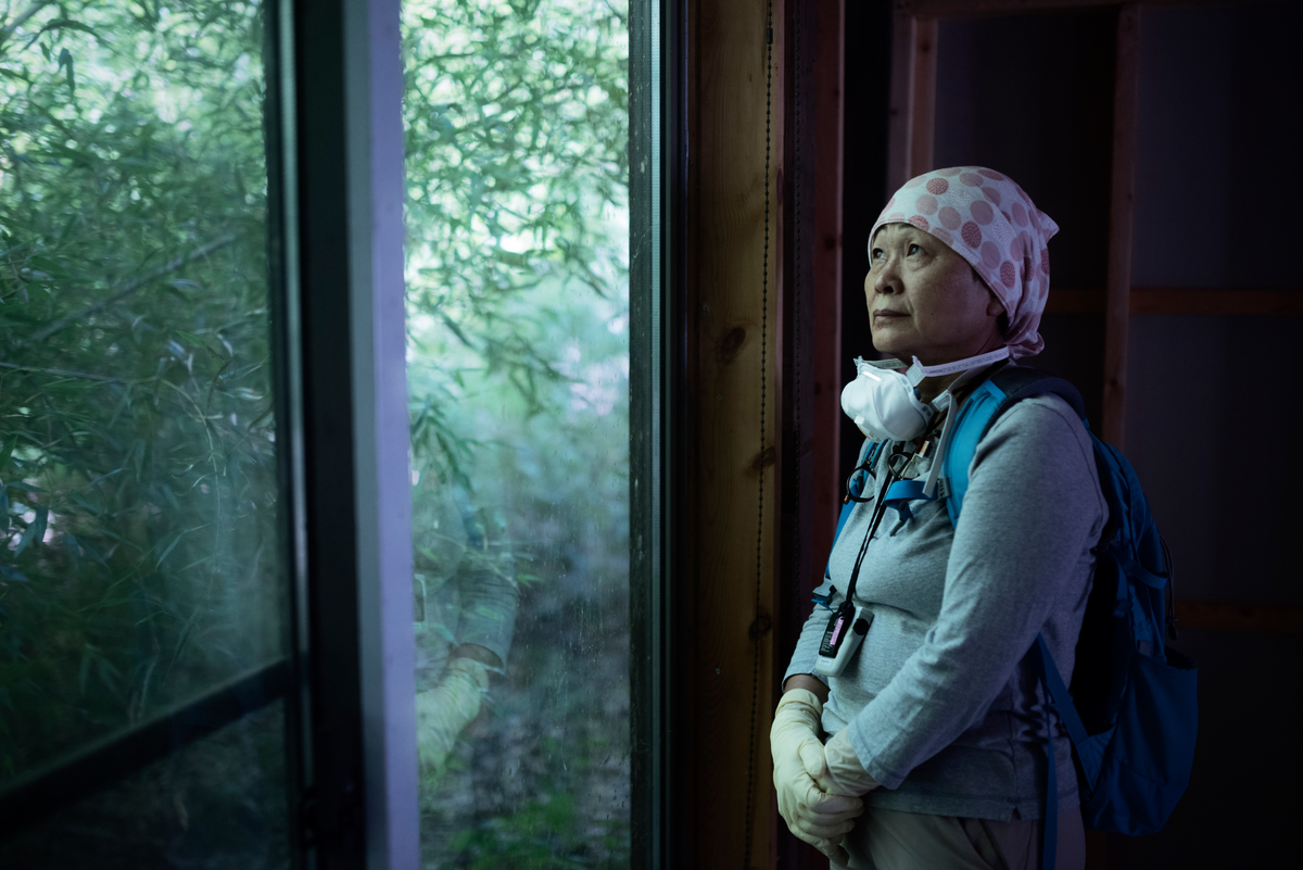 因核災撤離家園的菅野太太於2017年重回福島的家，因該區仍是輻射值超標的歸還困難區，僅能短暫停留。© Christian Åslund / Greenpeace