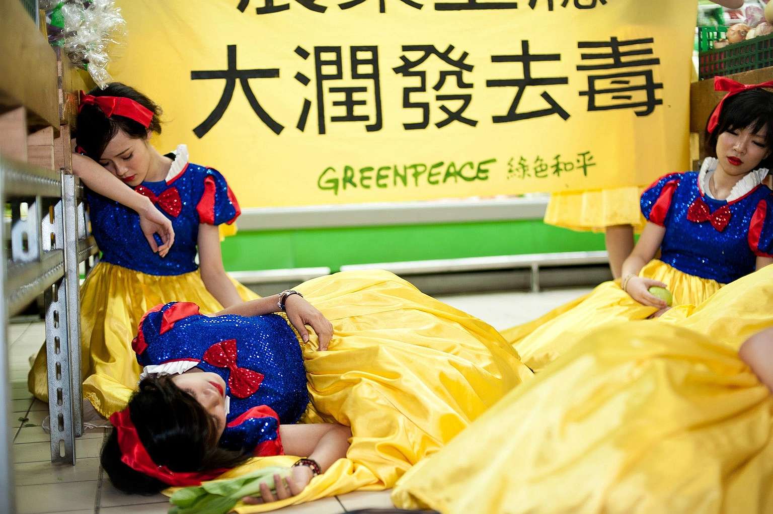 2012年，綠色和平行動者打扮成白雪公主，因吃了殘留過多農藥的毒蘋果昏倒在超市，要求政府及企業重視農藥危害及食品安全。© Greenpeace