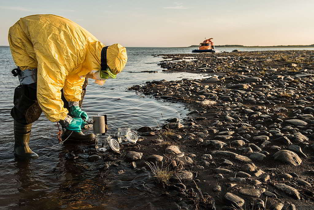 綠色和平調查團隊身著防護衣，抽取河水樣本，以調查Norilsk Nickel漏油事故對環境造成的影響。諾里爾斯是地球最北端的城市，有15萬人口，也是北極圈內第二大城市。